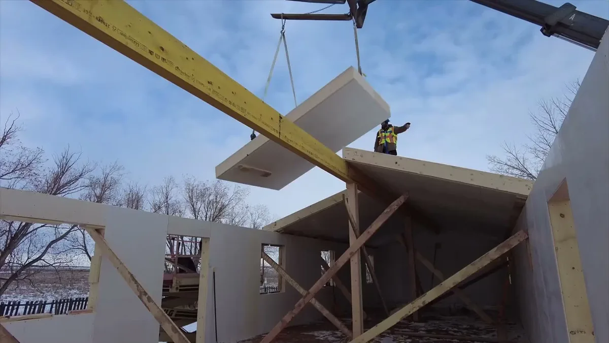 A telehandler lifting a Titanwall roof panel into place while the crew guides it